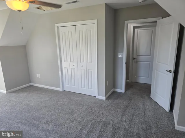 a view of an empty room with closet and mirror