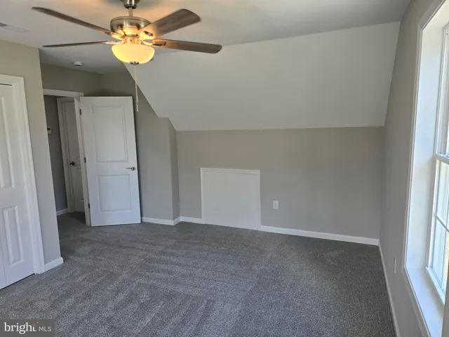 an empty room with a chandelier fan and closet area