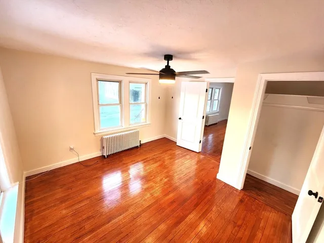 an empty room with wooden floor and ceiling fan
