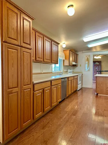 a kitchen with stainless steel appliances granite countertop a refrigerator a sink dishwasher and wooden cabinets with wooden floor