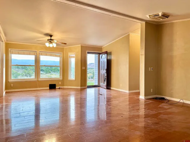 a view of an empty room with window and wooden floor