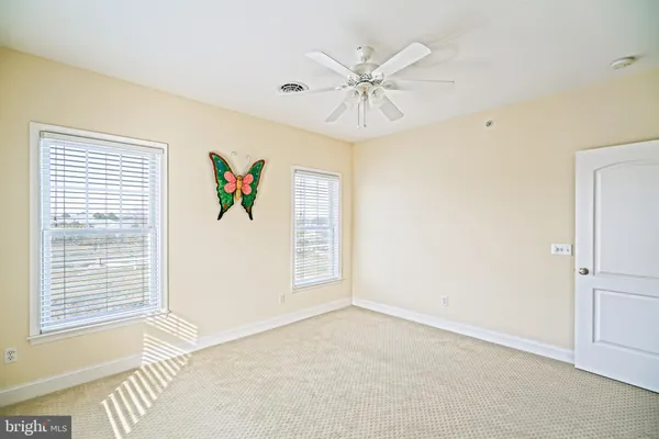 an empty room with a ceiling fan and windows