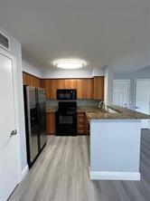 1001 Crystal Way, Unit B Delray Beach, FL 33444 - Photo 5 of 12 a kitchen with stainless steel appliances kitchen island granite countertop a refrigerator and a sink