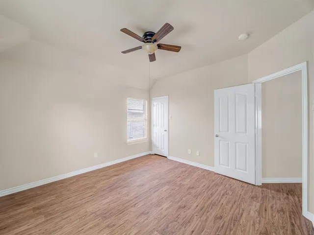 a view of empty room with wooden floor and ceiling fan