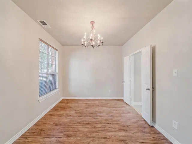 a view of a chandelier in an empty room with wooden floor and a window