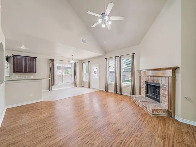 a view of an empty room with wooden floor fireplace and a window