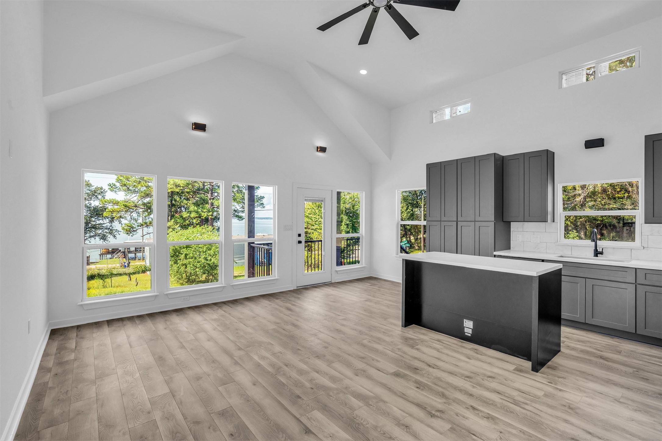 117 Rain Forest Road Onalaska, TX 77360 - Photo 22 of 30 Bright and spacious open-concept living area features large windows with stunning water views, vaulted ceilings, sleek gray cabinetry, and modern finishes.