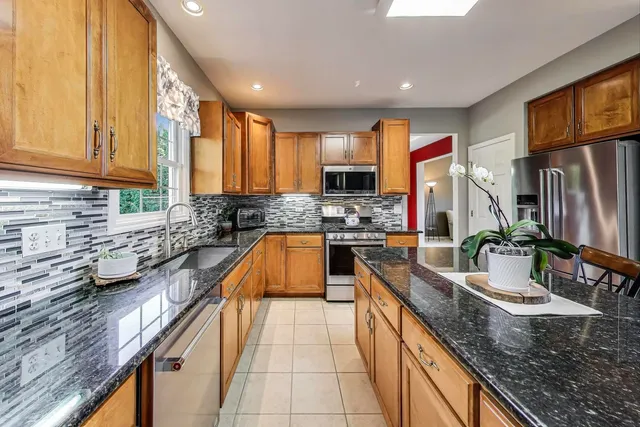 a kitchen with stainless steel appliances granite countertop a sink a stove counter space and a window