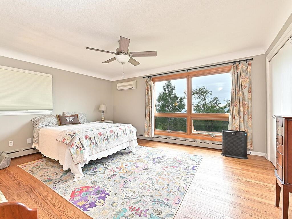 7 Kent Lane Silver Bay, MN 55614 - Photo 18 of 32 Bedroom featuring a baseboard heating unit, ceiling fan, light wood-style floors, and an AC wall unit