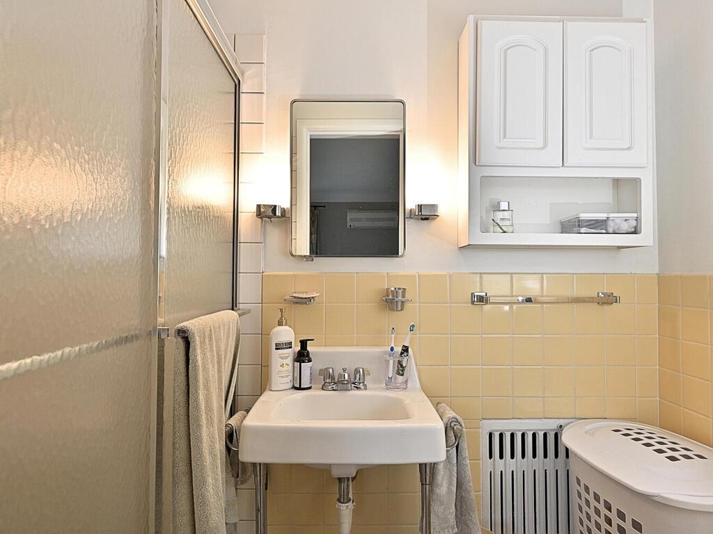 7 Kent Lane Silver Bay, MN 55614 - Photo 19 of 32 Full bath featuring a stall shower, tile walls, radiator, and a wainscoted wall