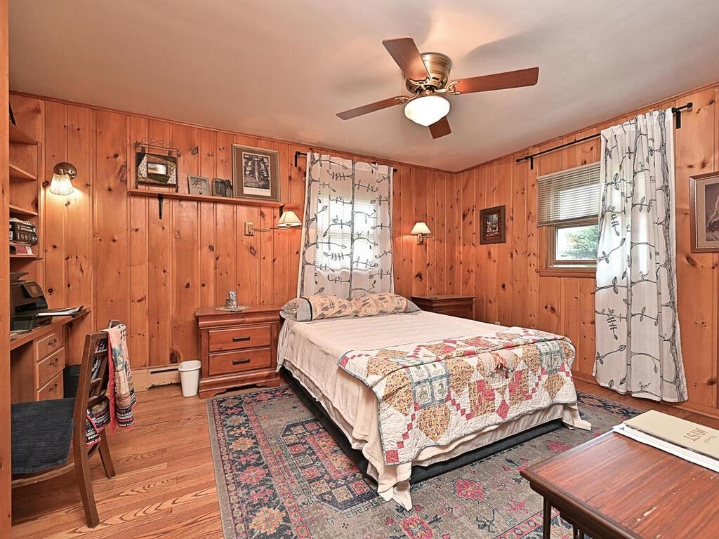 7 Kent Lane Silver Bay, MN 55614 - Photo 20 of 32 Bedroom with wooden walls, light wood-style flooring, ceiling fan, and baseboard heating