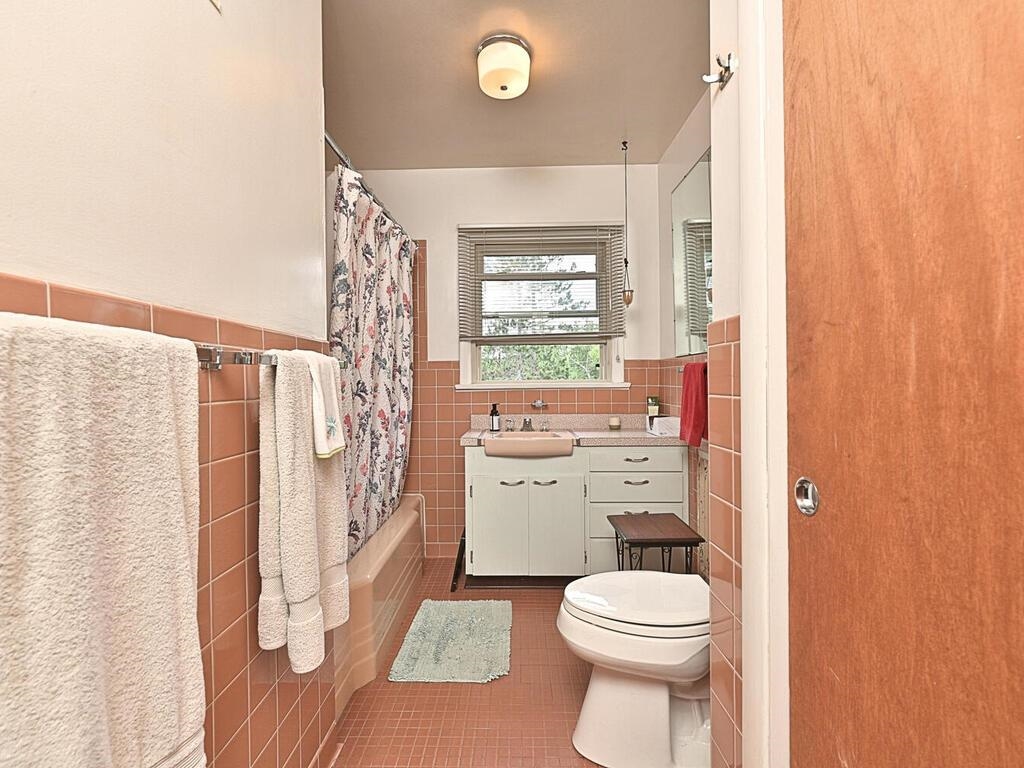 7 Kent Lane Silver Bay, MN 55614 - Photo 21 of 32 Full bathroom featuring dark tile patterned floors, shower / bath combo, tile walls, vanity, and a wainscoted wall
