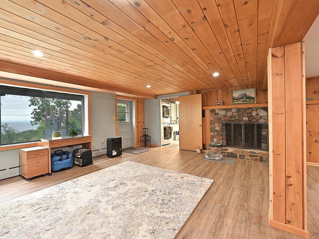 7 Kent Lane Silver Bay, MN 55614 - Photo 23 of 32 Unfurnished living room with light wood finished floors, a stone fireplace, wood ceiling, recessed lighting, and washer / dryer