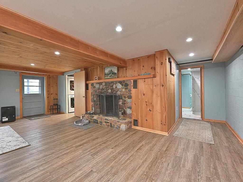 7 Kent Lane Silver Bay, MN 55614 - Photo 25 of 32 Unfurnished living room featuring beam ceiling, wood walls, a fireplace, wood finished floors, and recessed lighting