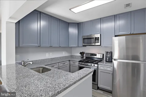a kitchen with granite countertop stainless steel appliances cabinets a sink and a counter top space