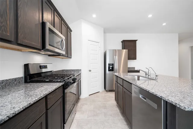 a kitchen with stainless steel appliances granite countertop a sink a stove and a refrigerator