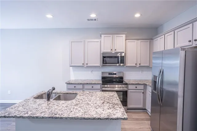 a kitchen with kitchen island granite countertop a sink a stove and refrigerator