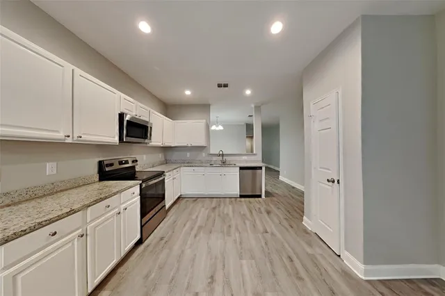 a large kitchen with stainless steel appliances granite countertop a lot of counter space and wooden floor