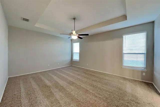 an empty room with a chandelier fan and windows