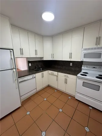 a kitchen with granite countertop white cabinets and white appliances