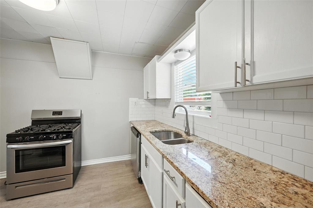204 Graham Avenue Bonham, TX 75418 - Photo 3 of 21 Kitchen with stainless steel appliances, light stone countertops, light wood-style flooring, decorative backsplash, and white cabinets