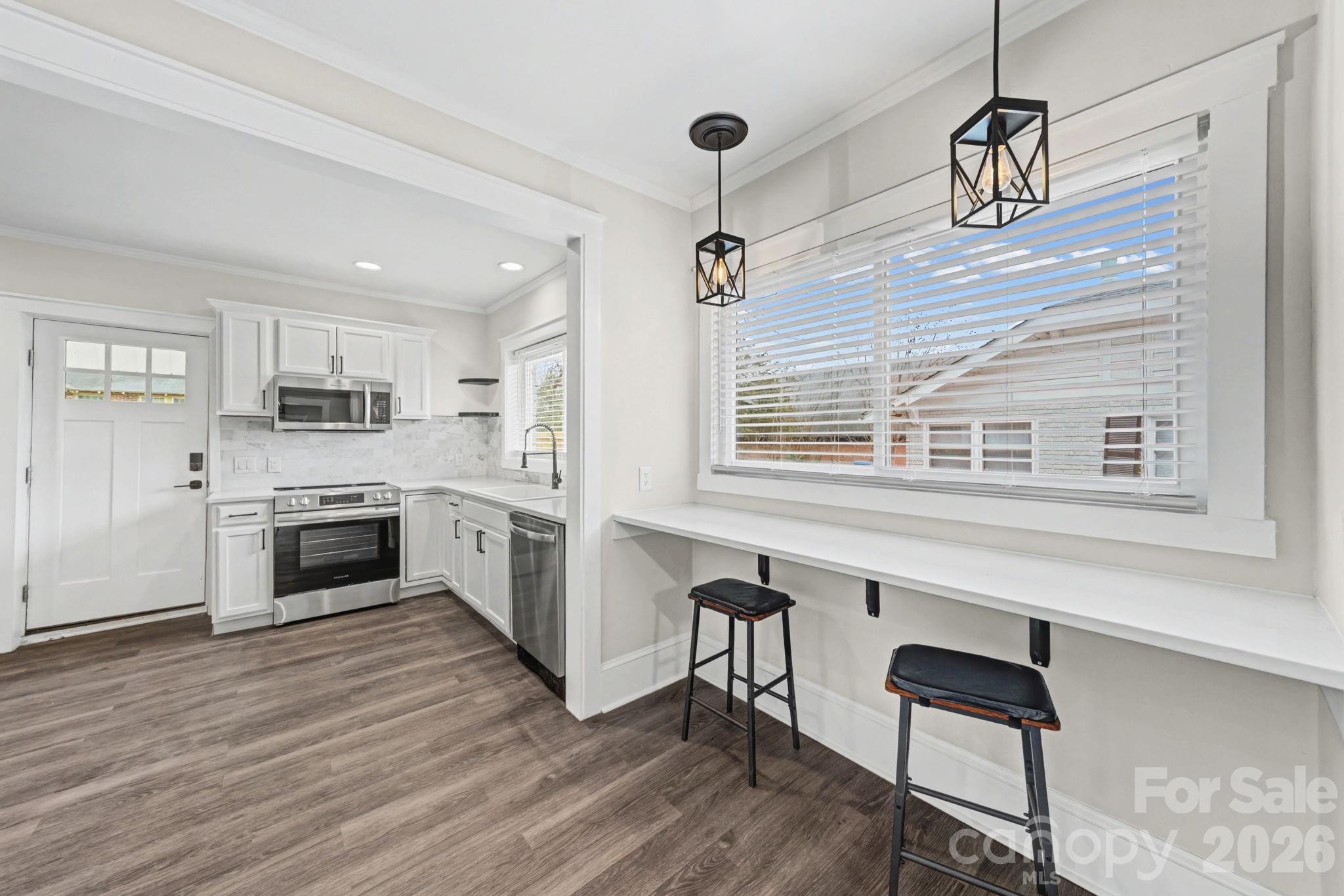 1132 East Main Street Albemarle, NC 28001 - Photo 12 of 25 a kitchen with stainless steel appliances a stove a sink dishwasher a refrigerator and white cabinets with wooden floor