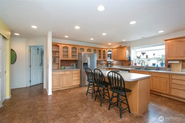 a kitchen with stainless steel appliances granite countertop a table chairs sink and window