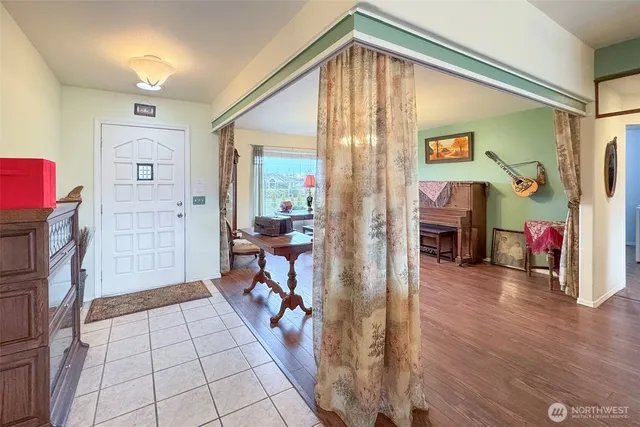 a view of a hallway to a livingroom with wooden floor and furniture
