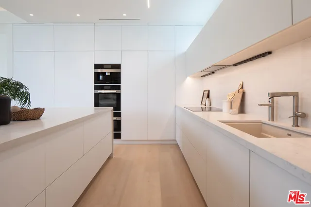 a large white kitchen with a sink and dishwasher
