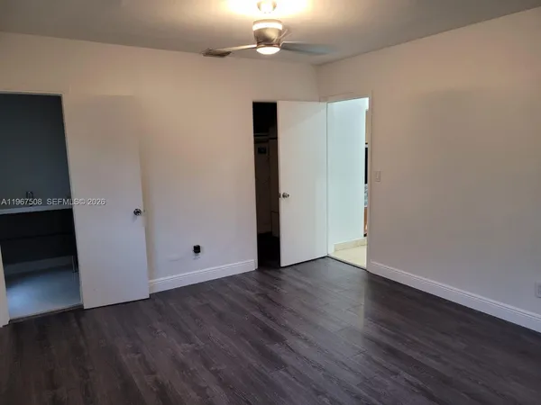 a view of an empty room with wooden floor and a cabinet