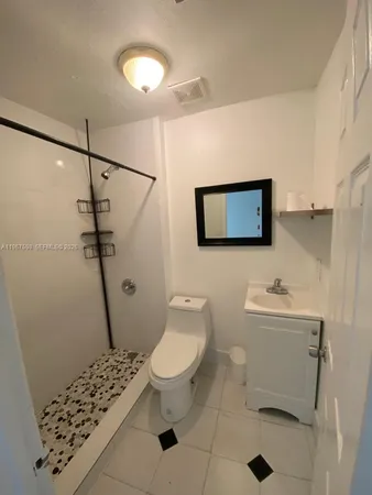 a bathroom with a sink a toilet a mirror and shower