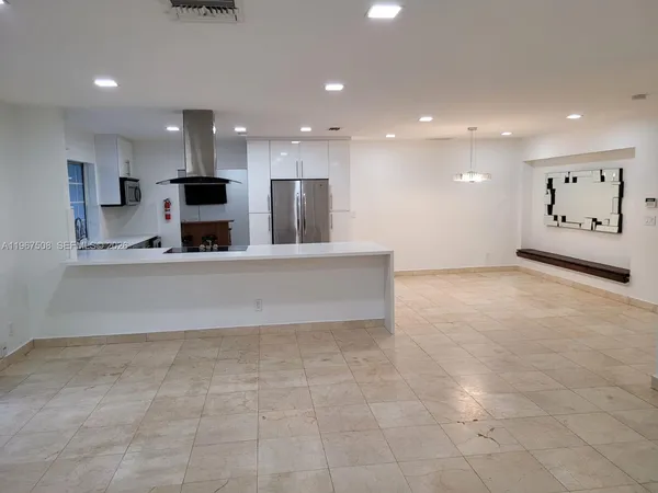 a large kitchen with stainless steel appliances kitchen island granite countertop a large counter top a sink and a refrigerator