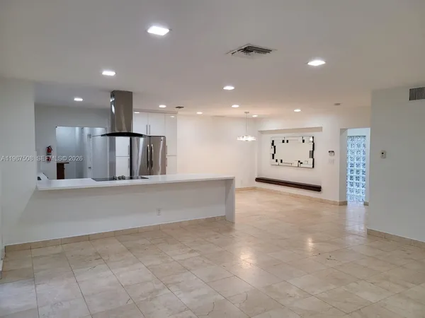 a large kitchen with stainless steel appliances a large counter top and a refrigerator
