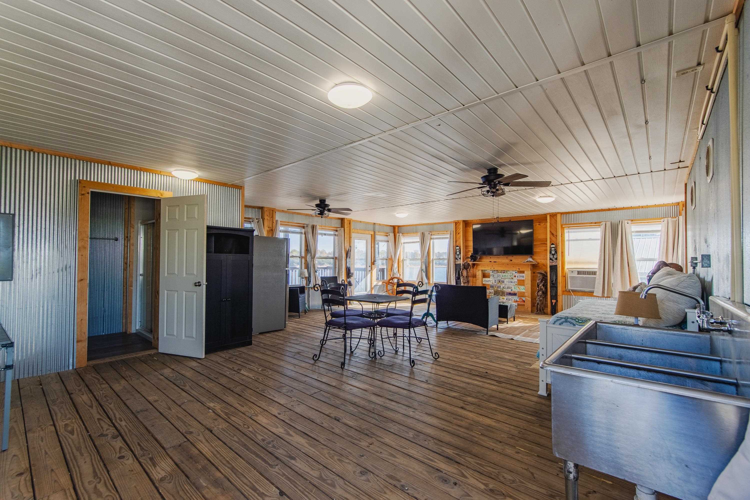 1111 Leaning Trees Lane Adamsville, TN 38310 - Photo 26 of 36 Spacious room featuring wood-finish flooring, a corrugated metal wall, and a beamed ceiling with flush-mount lighting and ceiling fans