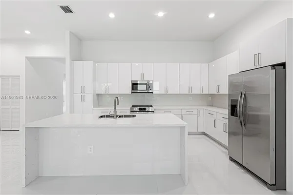 a kitchen with stainless steel appliances a refrigerator sink and white cabinets