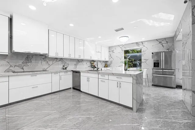 a kitchen with stainless steel appliances kitchen island granite countertop a refrigerator and white cabinets