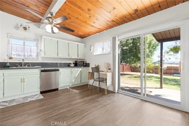 a kitchen with stainless steel appliances granite countertop a stove a sink and white cabinets with wooden floor next to windows