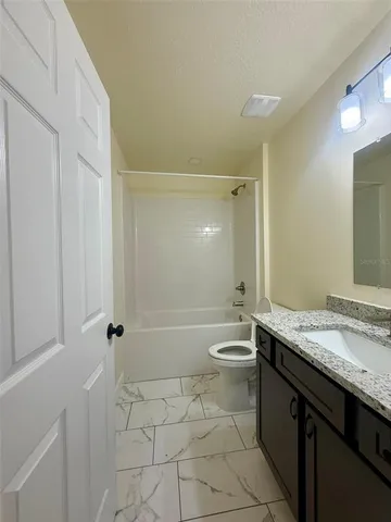 a bathroom with a granite countertop sink a toilet a mirror and bathtub