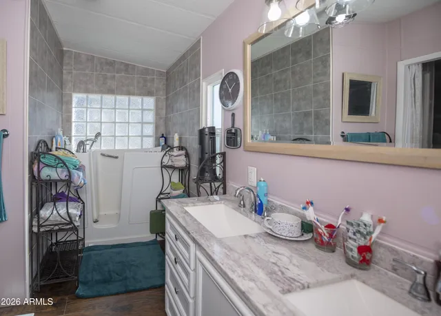 a bathroom with a granite countertop sink a mirror and shower