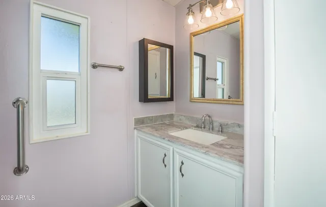a bathroom with a granite countertop sink vanity and mirror