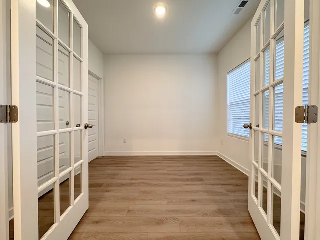 an empty room with wooden floor and windows