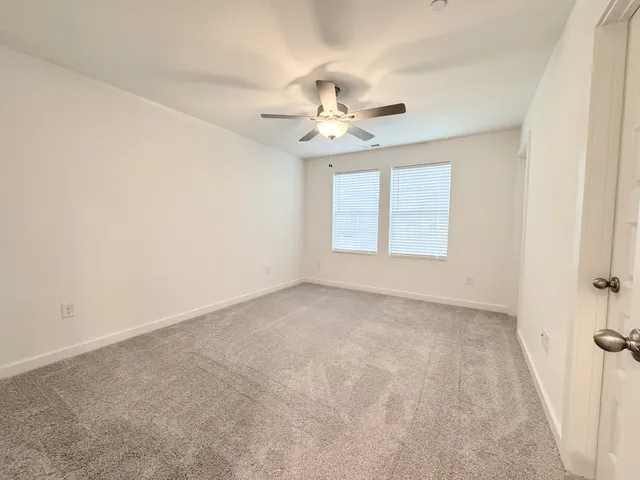 an empty room with windows and ceiling fan