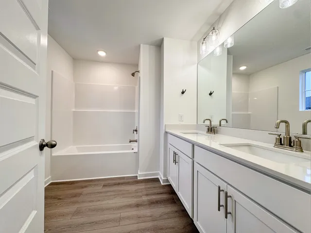 a bathroom with a tub sink double vanity granite tub and shower