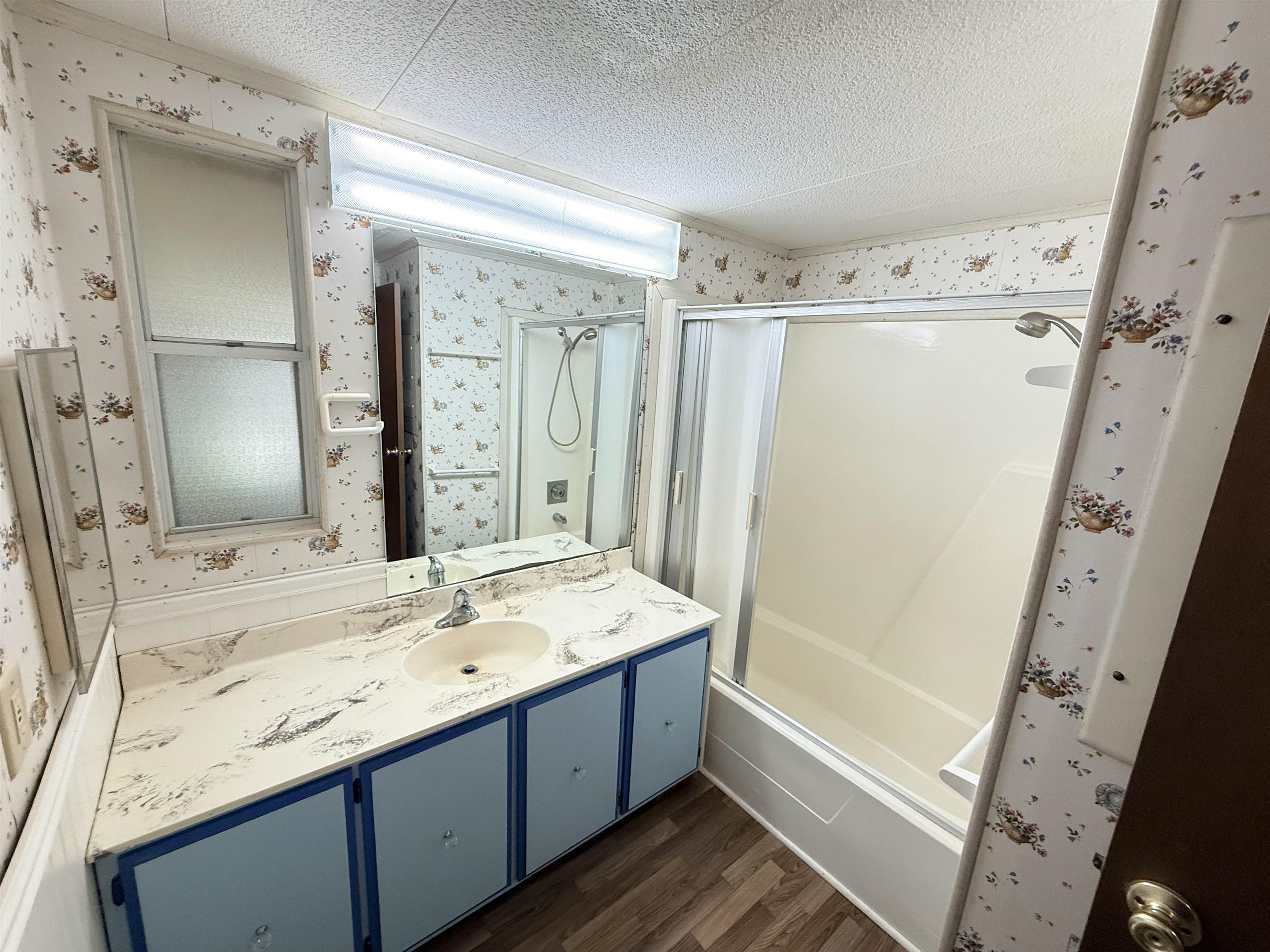 3043 Atlanta Circle Murrells Inlet, SC 29576 - Photo 18 of 36 Full bathroom with dark wood-style flooring, bath / shower combo with glass door, vanity, wallpapered walls, and a textured ceiling