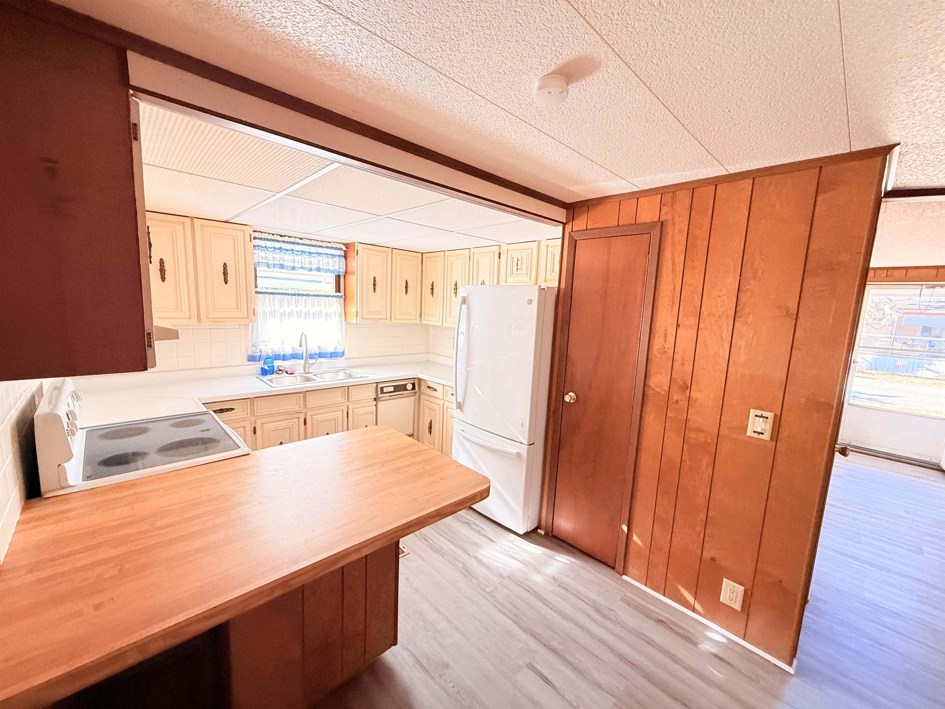 3043 Atlanta Circle Murrells Inlet, SC 29576 - Photo 9 of 36 Kitchen with light countertops, white appliances, light wood finished floors, a peninsula, and wooden walls