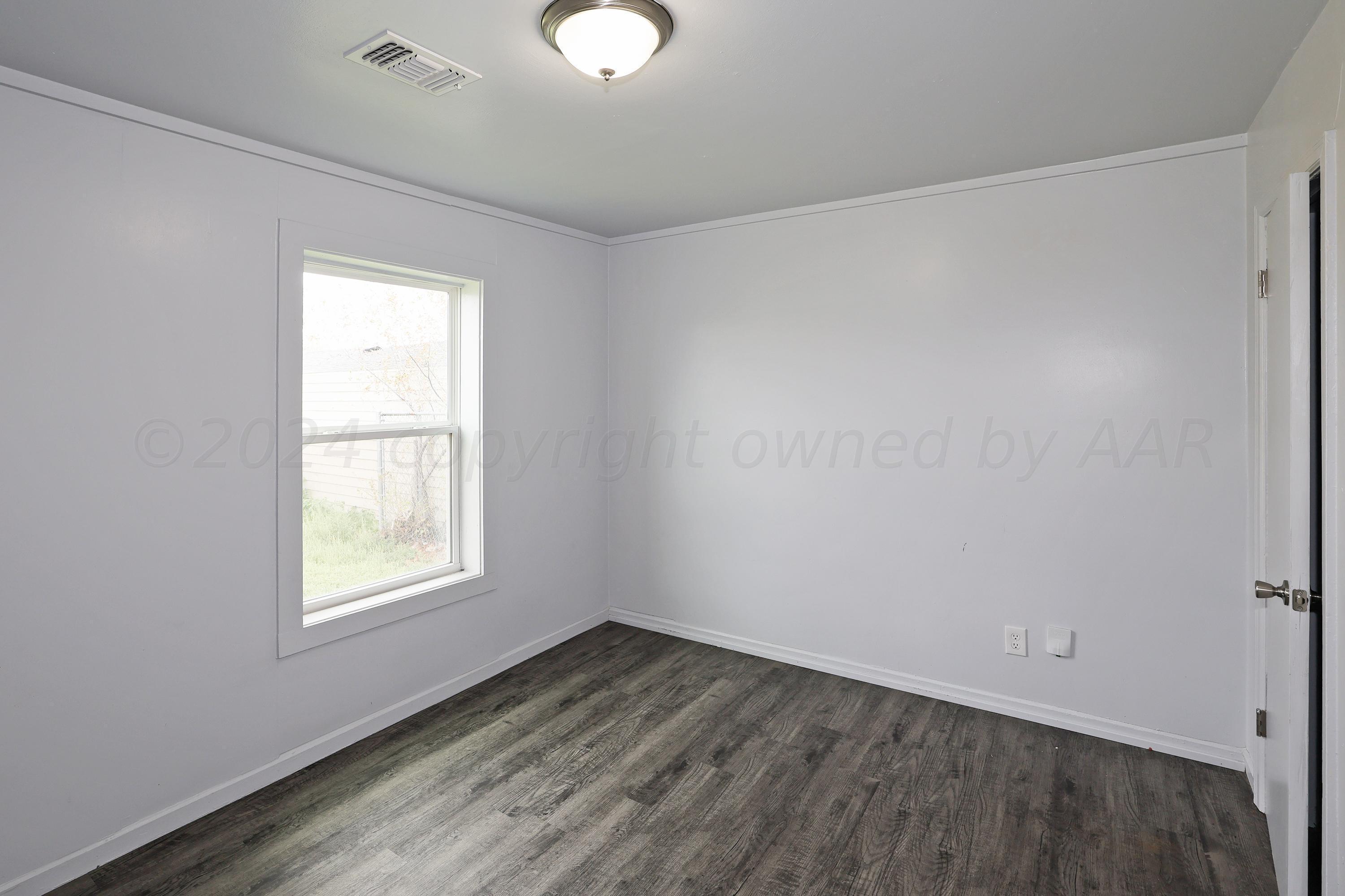 3703 South Monroe Street Amarillo, TX 79110 - Photo 12 of 14 an empty room with wooden floor and windows