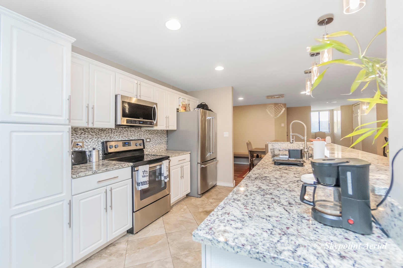 3231 West 184th Street, Unit 2B Homewood, IL 60430 - Photo 7 of 22 a kitchen with stainless steel appliances granite countertop a stove top oven a sink dishwasher a dining table and chairs with wooden floor