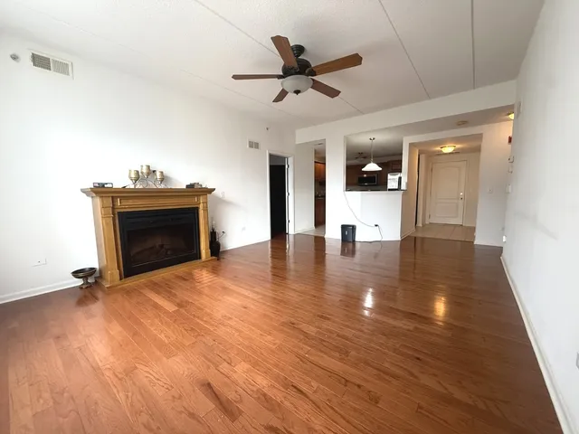 a living room with wooden floor and a ceiling fan