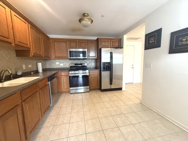 a large kitchen with stainless steel appliances granite countertop a stove top oven a sink dishwasher and a refrigerator