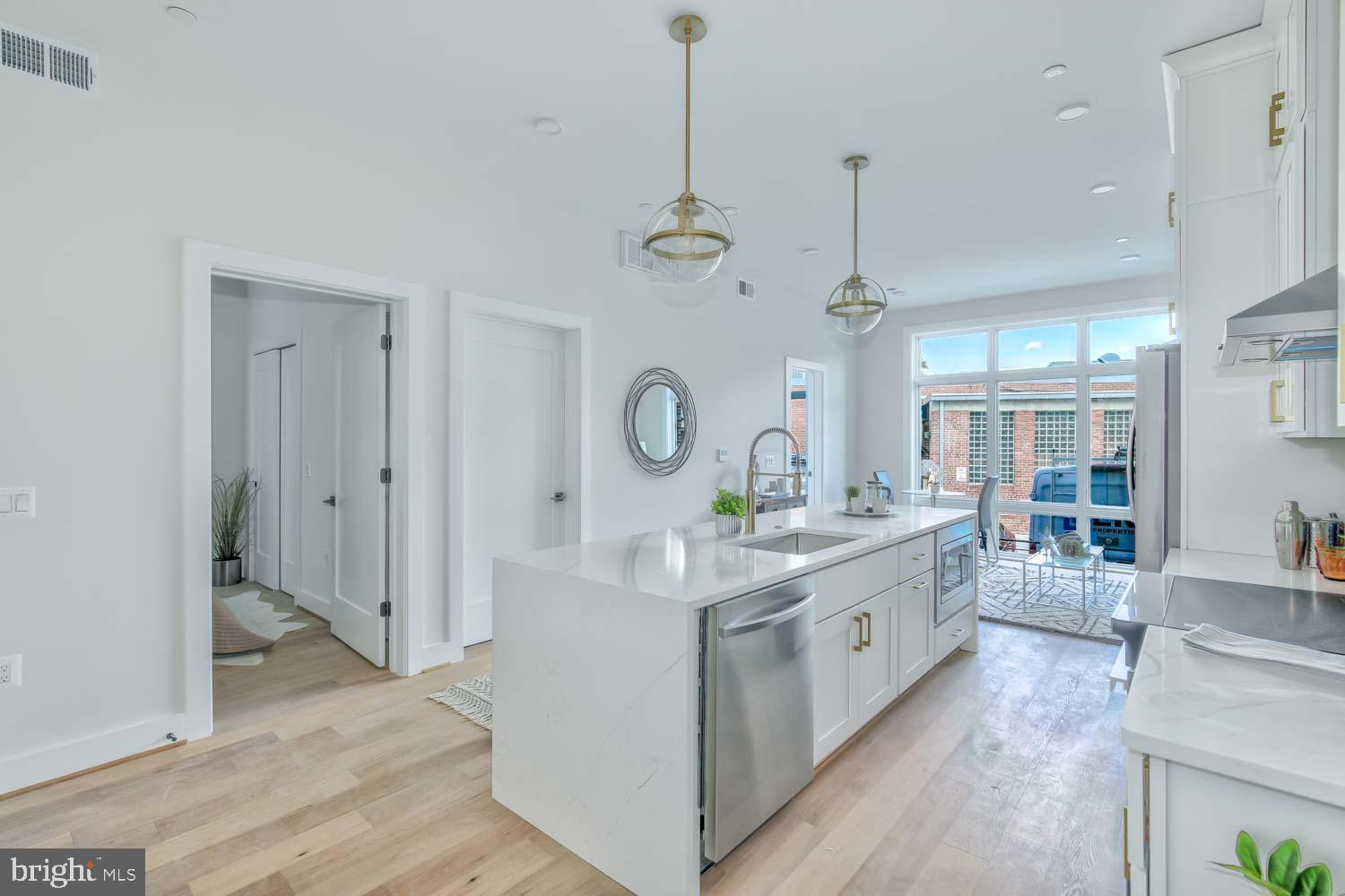 a large white kitchen with a large window a sink and cabinets